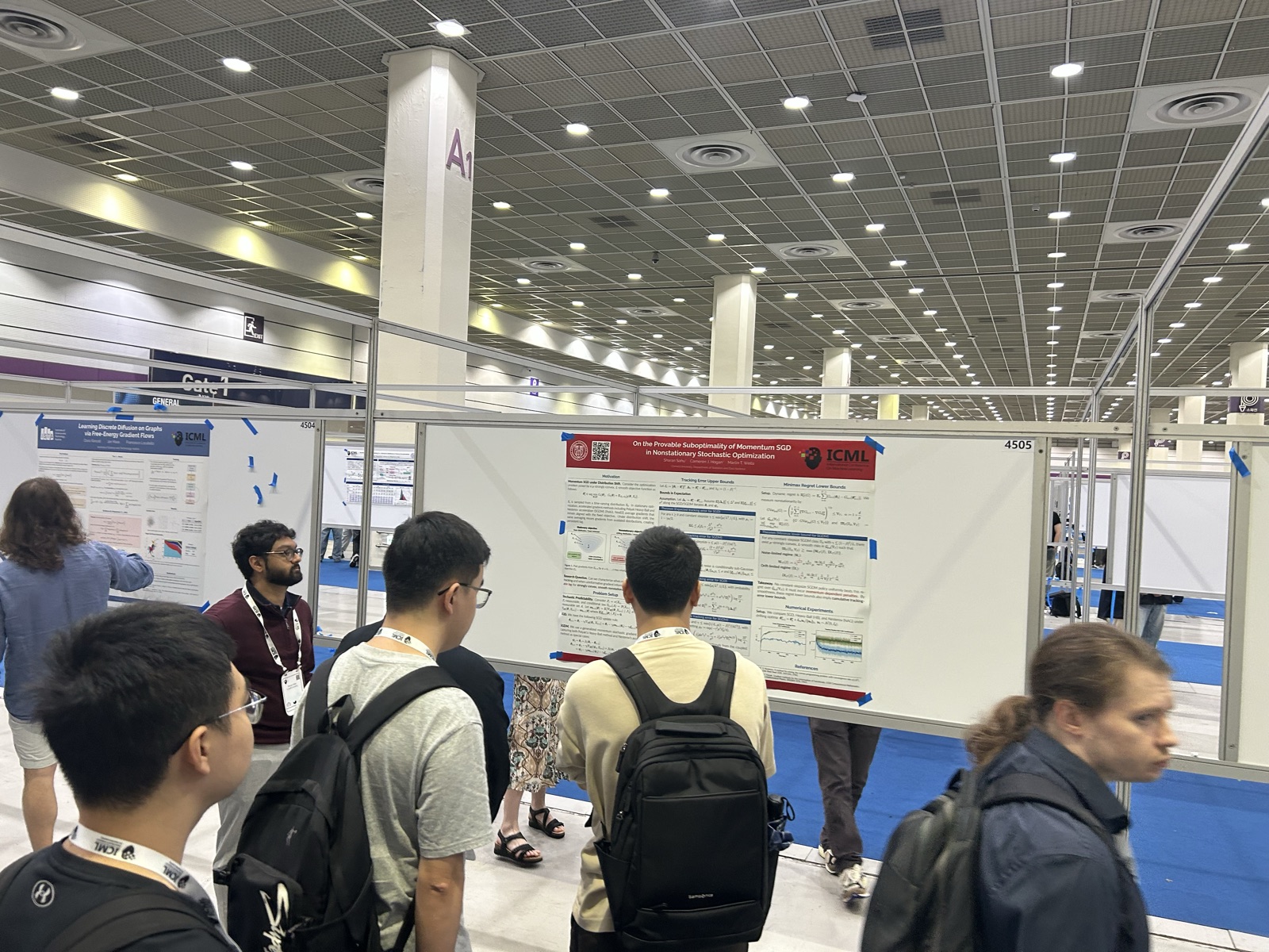 Talking through the poster with attendees at ICML 2026